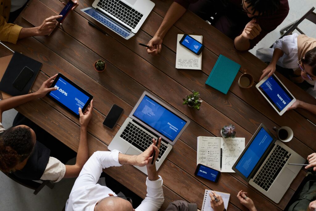Home - consultoria y gestion publica colombia Overhead view of a diverse team discussing around a wooden table, using technology.